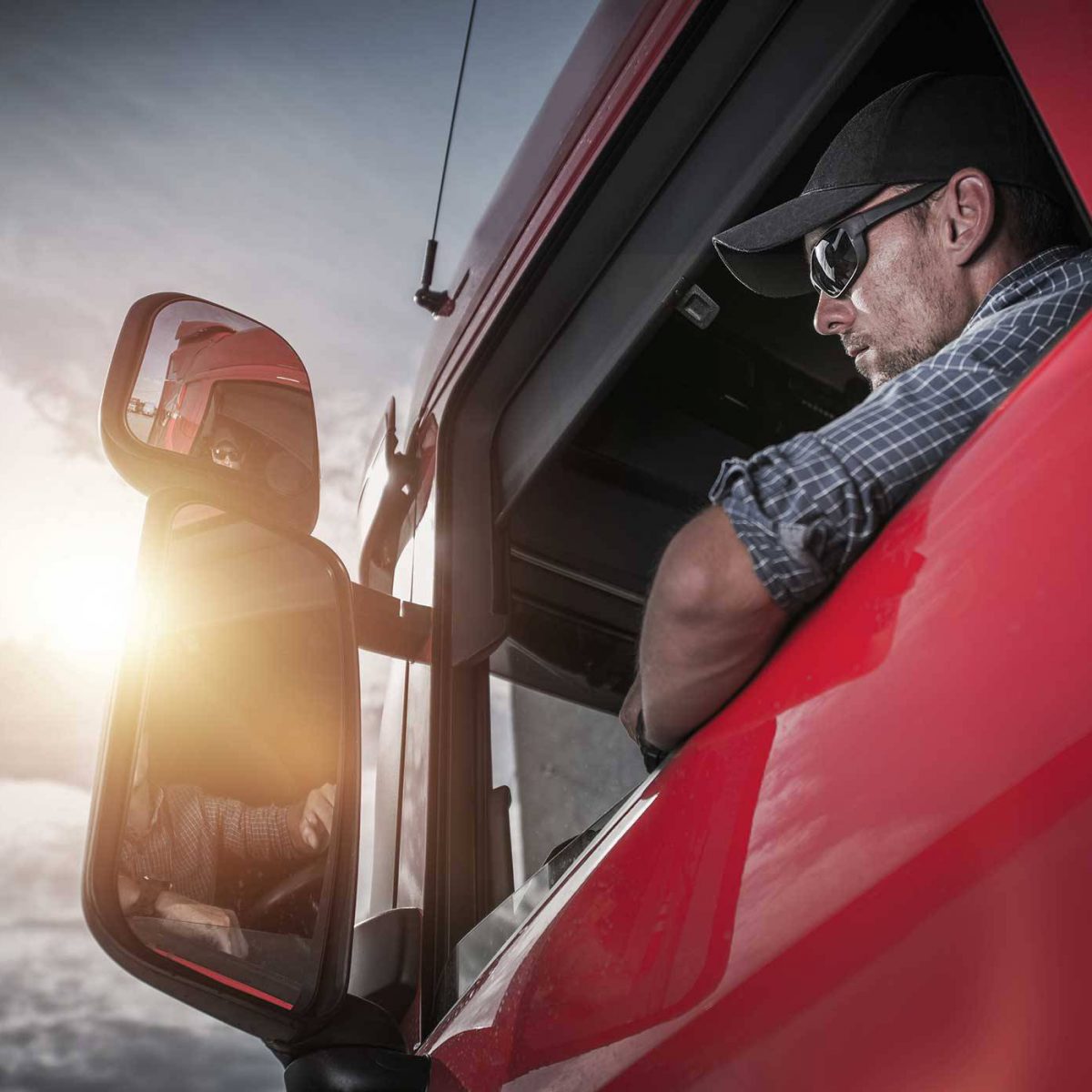 man looking out the open window of a semi truck as he considers truck repair