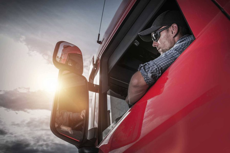 man looking out the open window of a semi truck as he considers truck repair