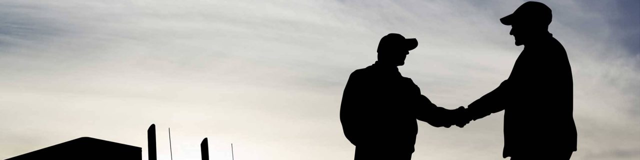 silhouette of two men shaking hands near a semi truck