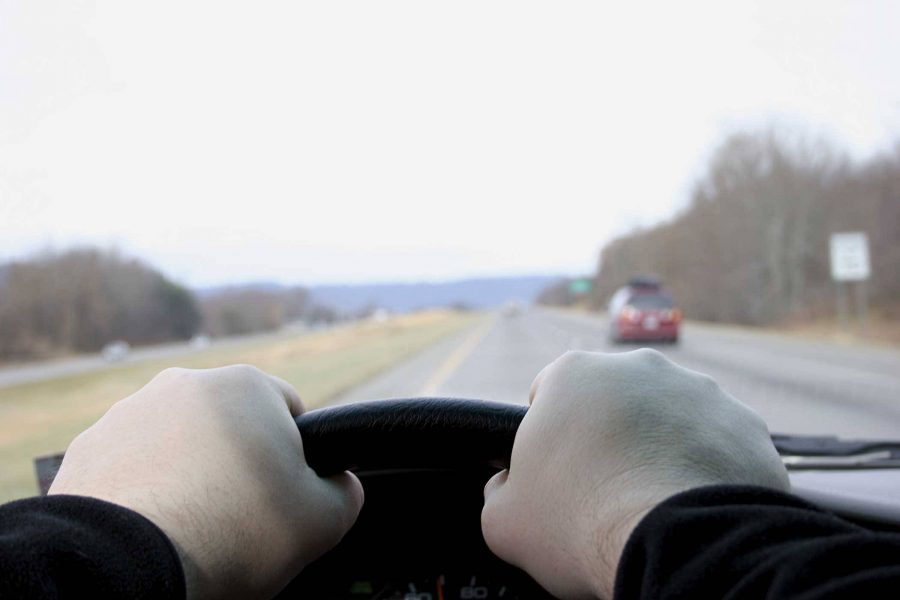 two caucasian hands gripping the steering wheel of a vehicle